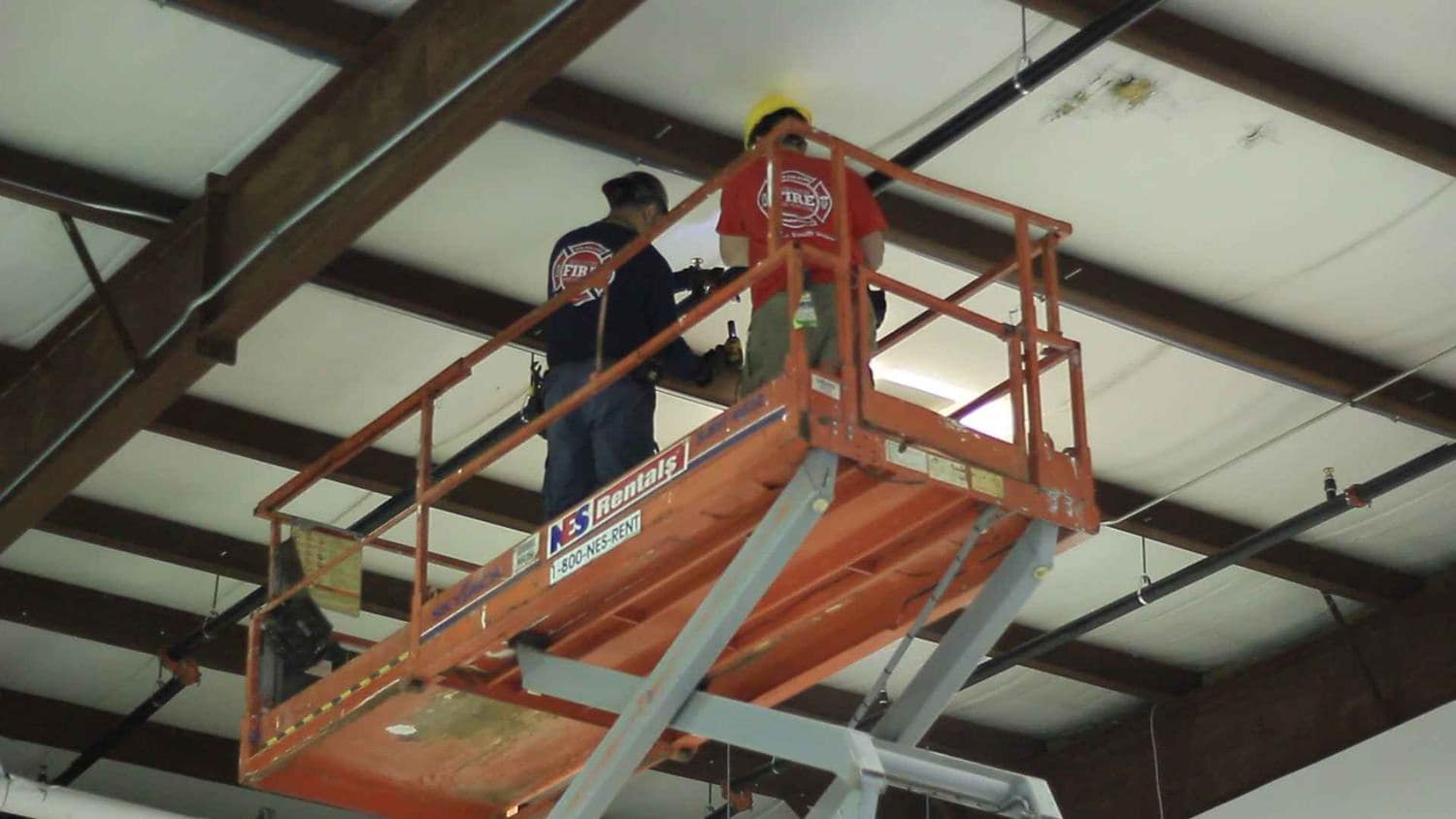 Solution Fire Prevention crew working from a lift in a commercial building